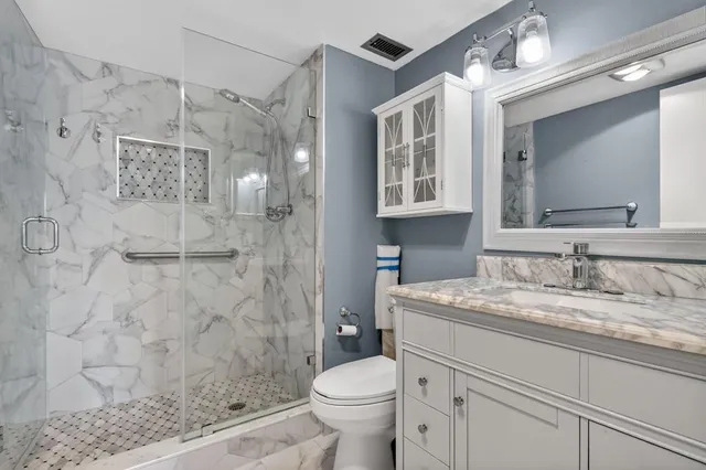 a bathroom with a granite countertop sink toilet and shower