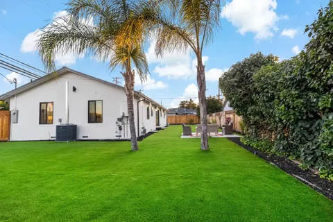 a kitchen with stainless steel appliances kitchen island granite countertop a stove a refrigerator a sink dishwasher a dining table and chairs with wooden floor