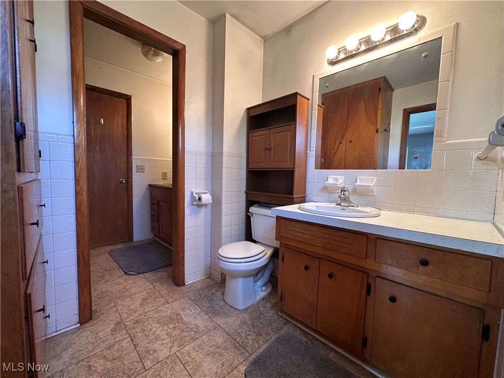 2829 Shellhart Road Barberton, OH 44203 - Photo 12 of 29 Full view of upper level full bathroom with wainscoting, vanity, tile walls, toilet, and tile patterned flooring