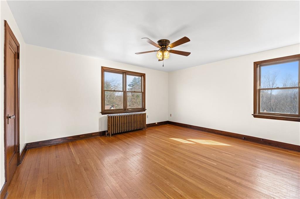 9715 Bellcrest Road Pittsburgh, PA 15237 - Photo 19 of 41 an empty room with wooden floor chandelier fan and windows