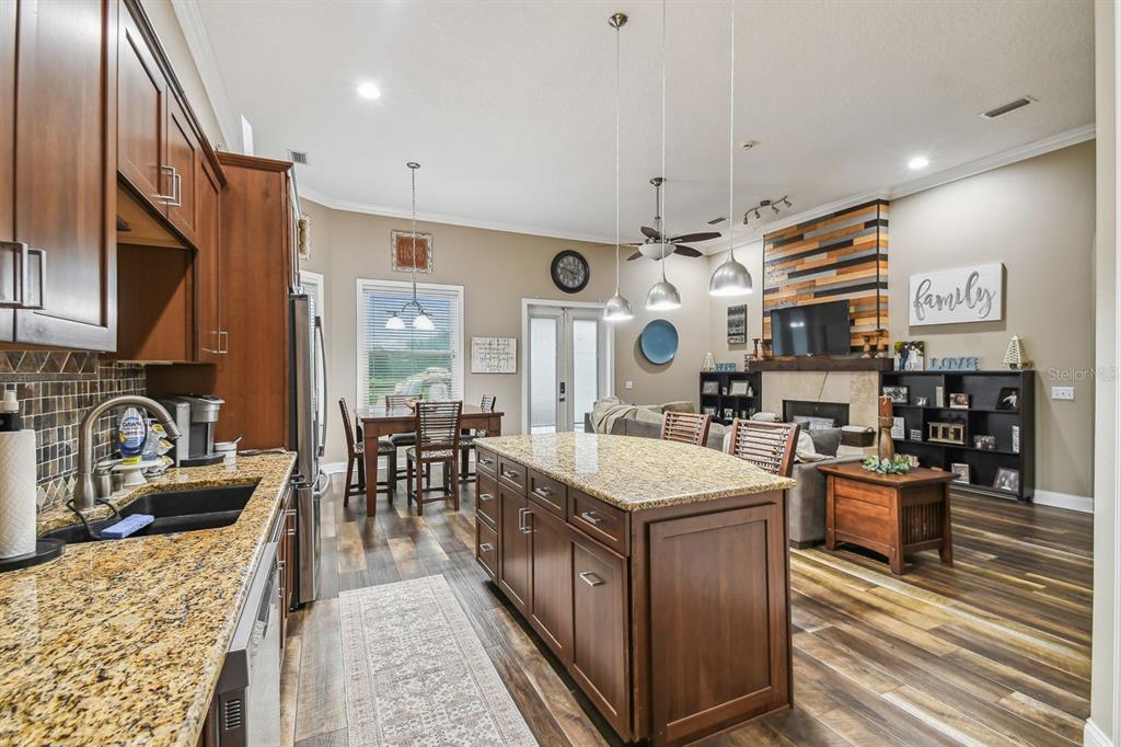 19315 Lake Pickett Road Orlando, FL 32820 - Photo 41 of 90 a large kitchen with kitchen island a stove a sink a dining table and chairs with wooden floor