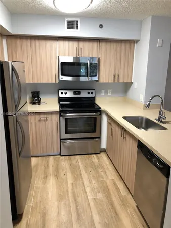 a kitchen with a sink a microwave a refrigerator and cabinets