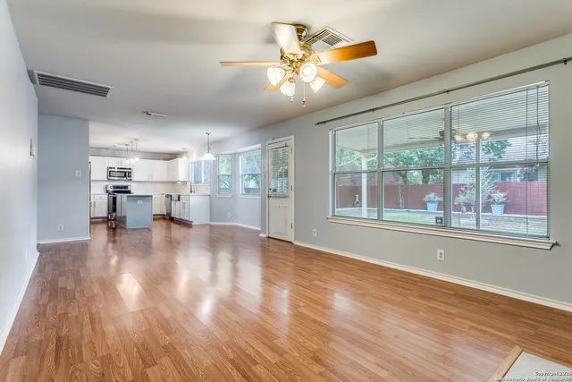 a view of empty room with wooden floor and fan