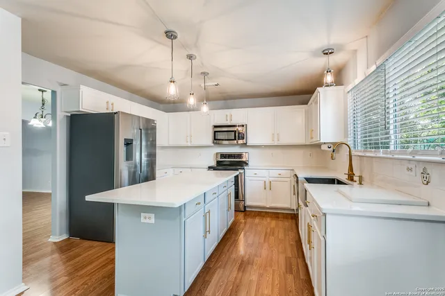 a kitchen with stainless steel appliances granite countertop a sink refrigerator and cabinets