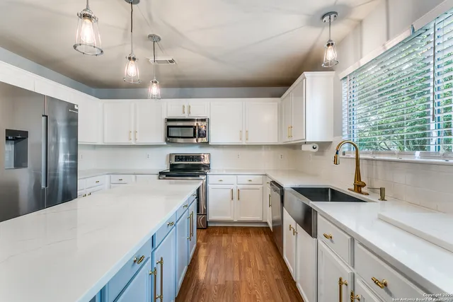 a kitchen with a sink a counter top space stainless steel appliances cabinets and a large window