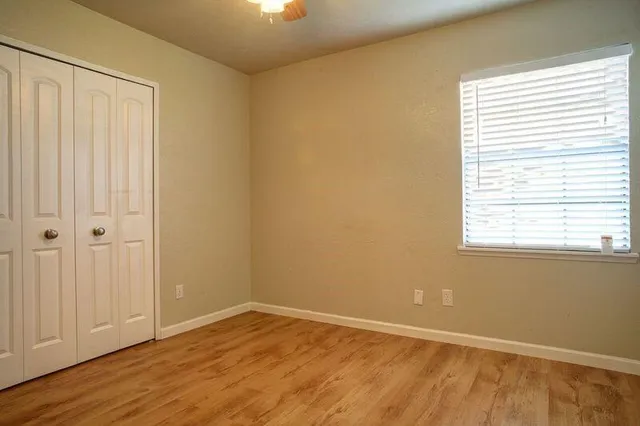 an empty room with wooden floor and windows
