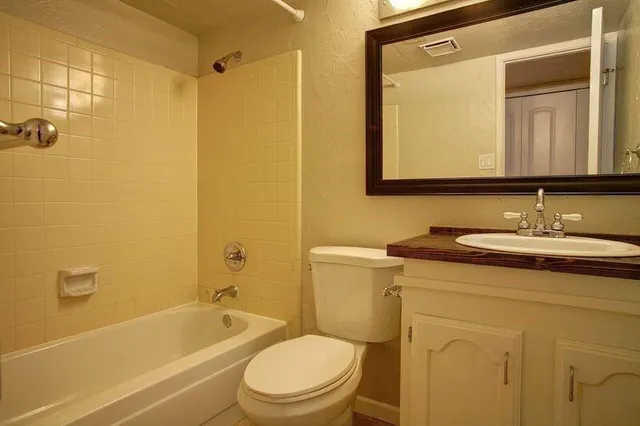 a bathroom with a granite countertop sink toilet and shower