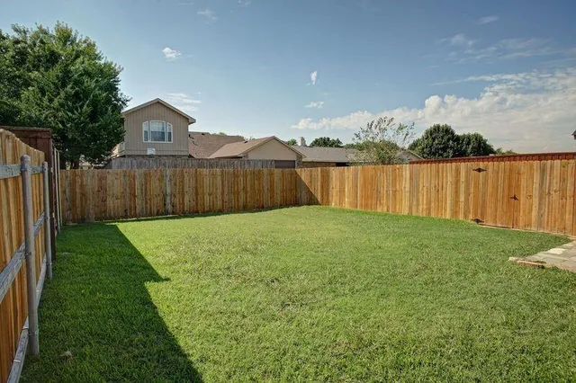 a view of a house with a yard and a large tree