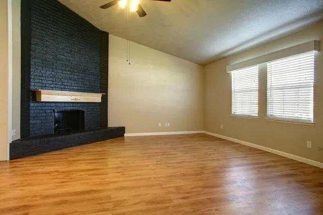 a view of empty room with wooden floor and fireplace