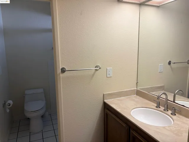 a bathroom with a granite countertop sink a toilet and a mirror