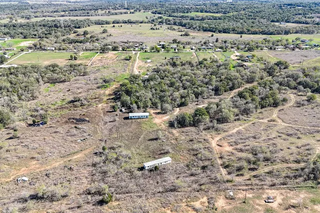 a view of a dry yard with trees and houses