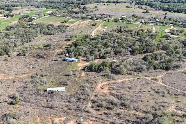 a view of a dry yard with green space and trees