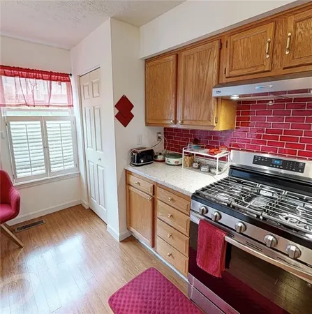 a kitchen with stainless steel appliances granite countertop a stove a sink dishwasher and cabinets with wooden floor