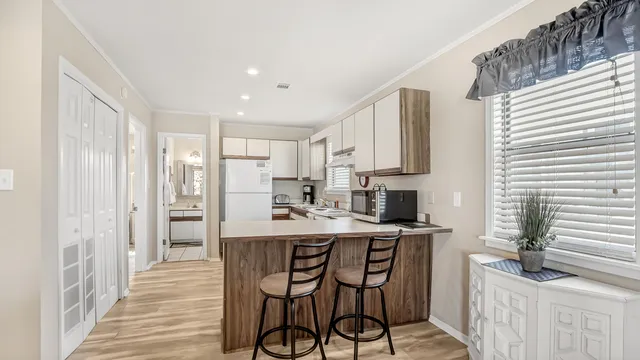 a kitchen with stainless steel appliances a dining table chairs refrigerator and sink