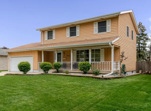 a front view of a house with a yard and green space