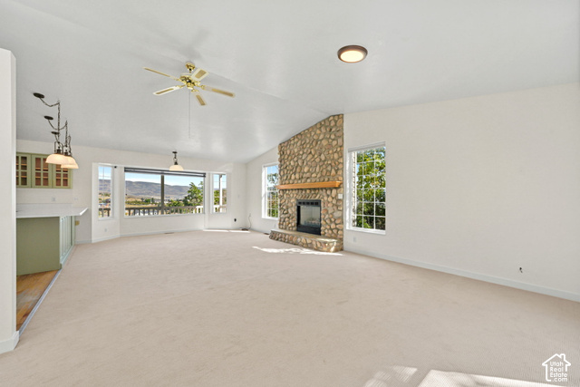Spacious room featuring a stone-clad fireplace with a wood mantel, multiple large windows, and a built-in wet bar with cabinetry