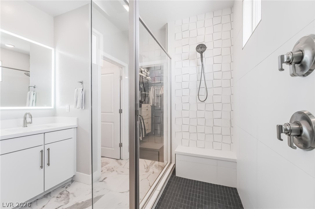 2166 Trivero Street Henderson, NV 89044 - Photo 31 of 61 A modern bathroom features a sleek vanity and a shower with an artistic tiled wall and built-in bench.
