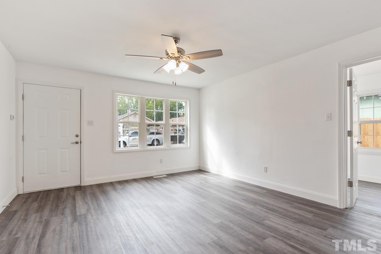 713 Quarry Street Raleigh, NC 27601 - Photo 13 of 26 an empty room with wooden floor chandelier fan and windows