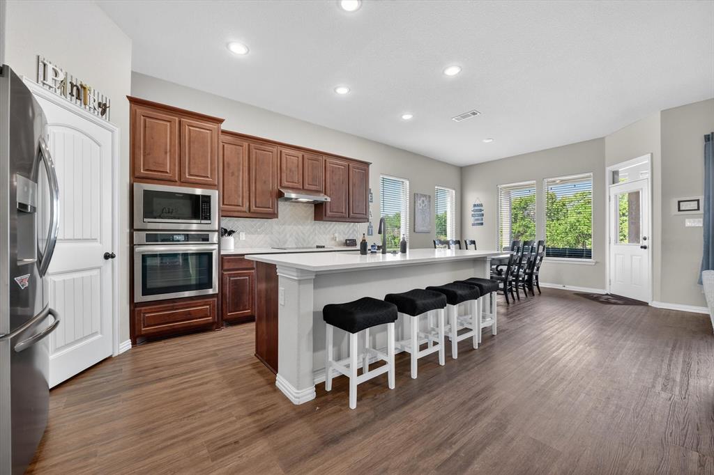150 Chester Road Springtown, TX 76082 - Photo 10 of 40 a kitchen with stainless steel appliances granite countertop a stove a refrigerator a sink a dining table and chairs with wooden floor