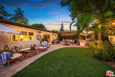 a view of a patio with table and chairs potted plants and a large tree