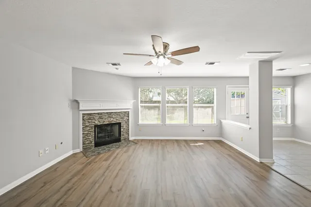 a view of an empty room with wooden floor fireplace and a window