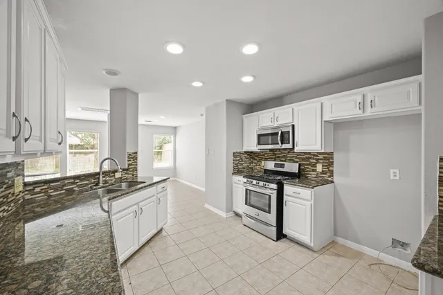 a kitchen with stainless steel appliances kitchen island granite countertop a stove and a sink