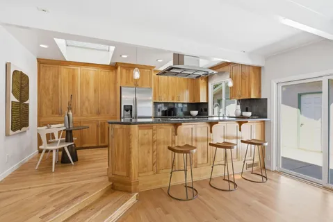 a kitchen with granite countertop a dining table chairs and a wooden floor