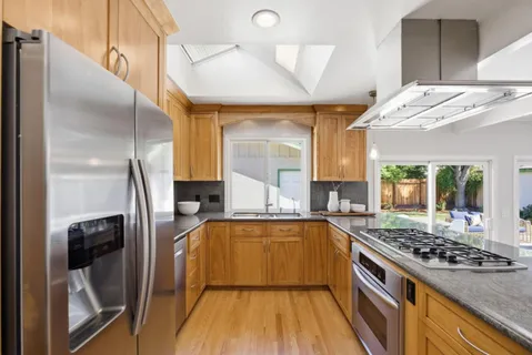 a kitchen with stainless steel appliances granite countertop a sink and wooden cabinets