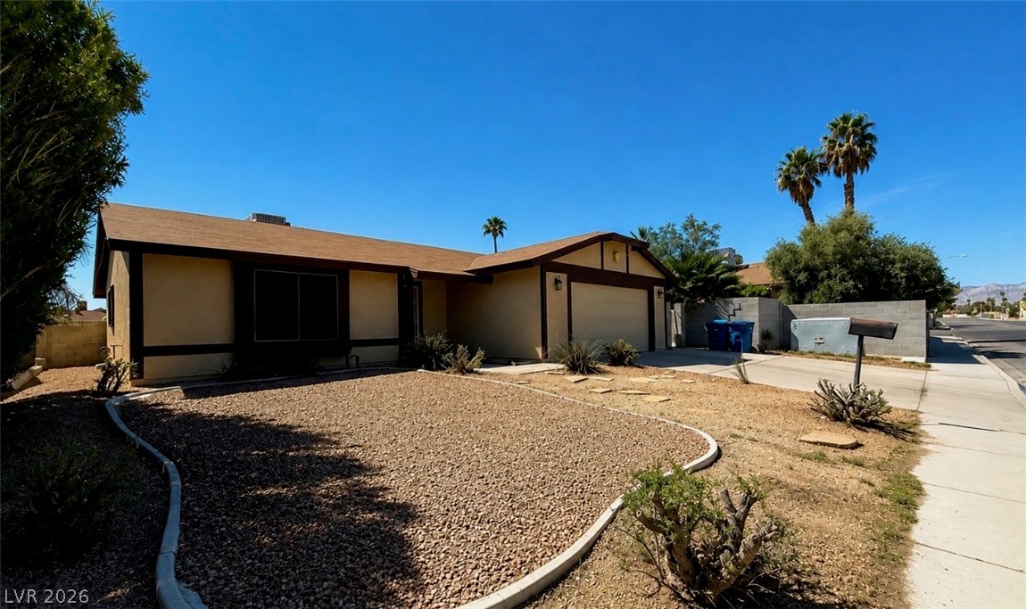 A classic ranch home features a neatly maintained front yard with desert landscaping and an attached garage.