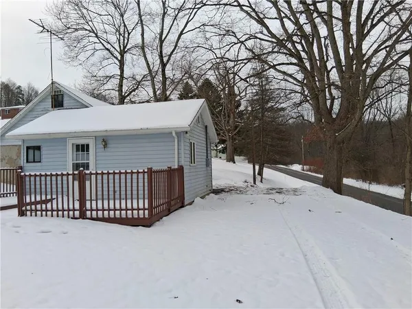 a view of a house with a wooden fence and a large tree