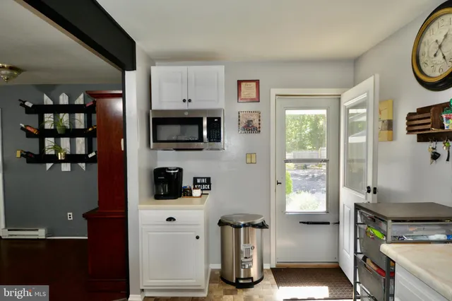 a kitchen with a refrigerator a stove top oven a clock and a window