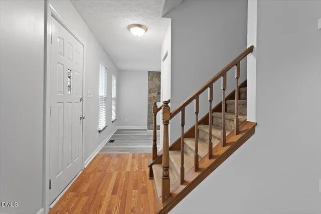 a view of staircase with lots of frames on wall and wooden floor