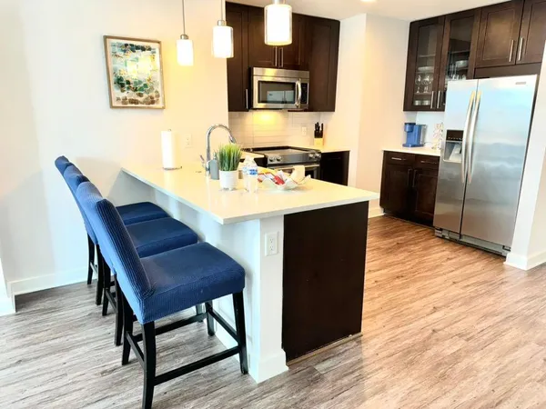 a kitchen with stainless steel appliances a table chairs and wooden floor