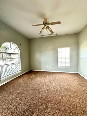 an empty room with a window and a ceiling fan