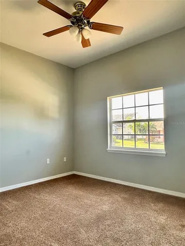 an empty room with a window and a fan
