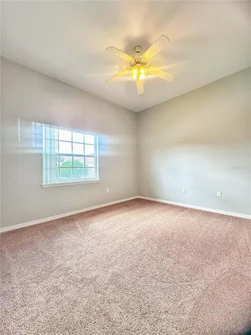 an empty room with a chandelier fan and windows