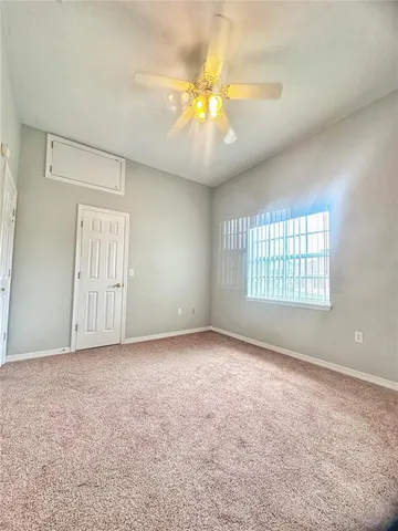 an empty room with windows and ceiling fan