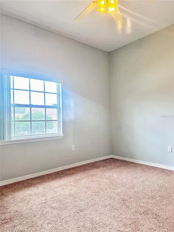 an empty room with a window and chandelier fan