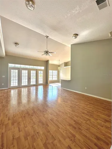 an empty room with wooden floor and windows