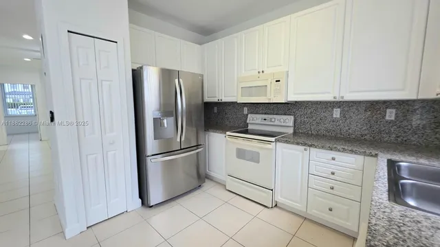 a kitchen with white cabinets and stainless steel appliances