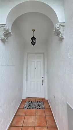 a view of an empty room with a chandelier fan and kitchen view