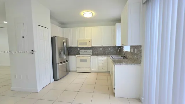 a kitchen with a refrigerator sink and cabinets