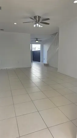 a view of an empty room with chandelier fan