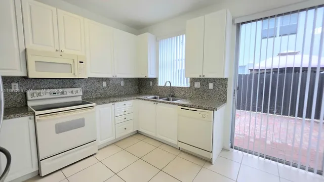 a kitchen with granite countertop white cabinets and white appliances