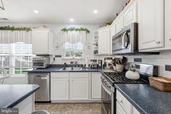 a kitchen with granite countertop a sink stainless steel appliances and cabinets
