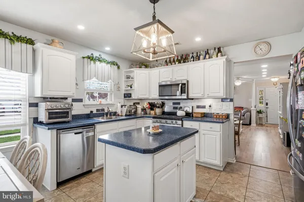 a kitchen with kitchen island granite countertop a sink cabinets and stainless steel appliances