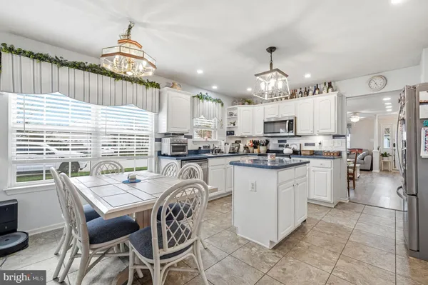 a kitchen with stainless steel appliances granite countertop a stove a sink dishwasher a refrigerator a dining table and chairs with wooden floor