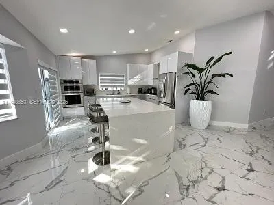 a kitchen with stainless steel appliances kitchen island granite countertop a refrigerator and a stove top oven