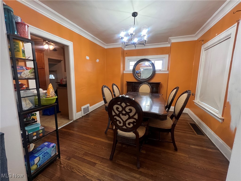 1686 Avalon Road Cleveland, OH 44112 - Photo 8 of 22 Dining room featuring a chandelier, baseboards, wood finished floors, visible vents, and ornamental molding