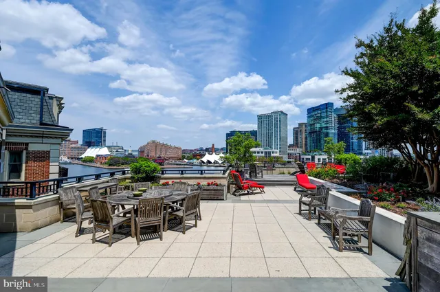 a swimming pool that has lawn chairs and a dining table with potted plants